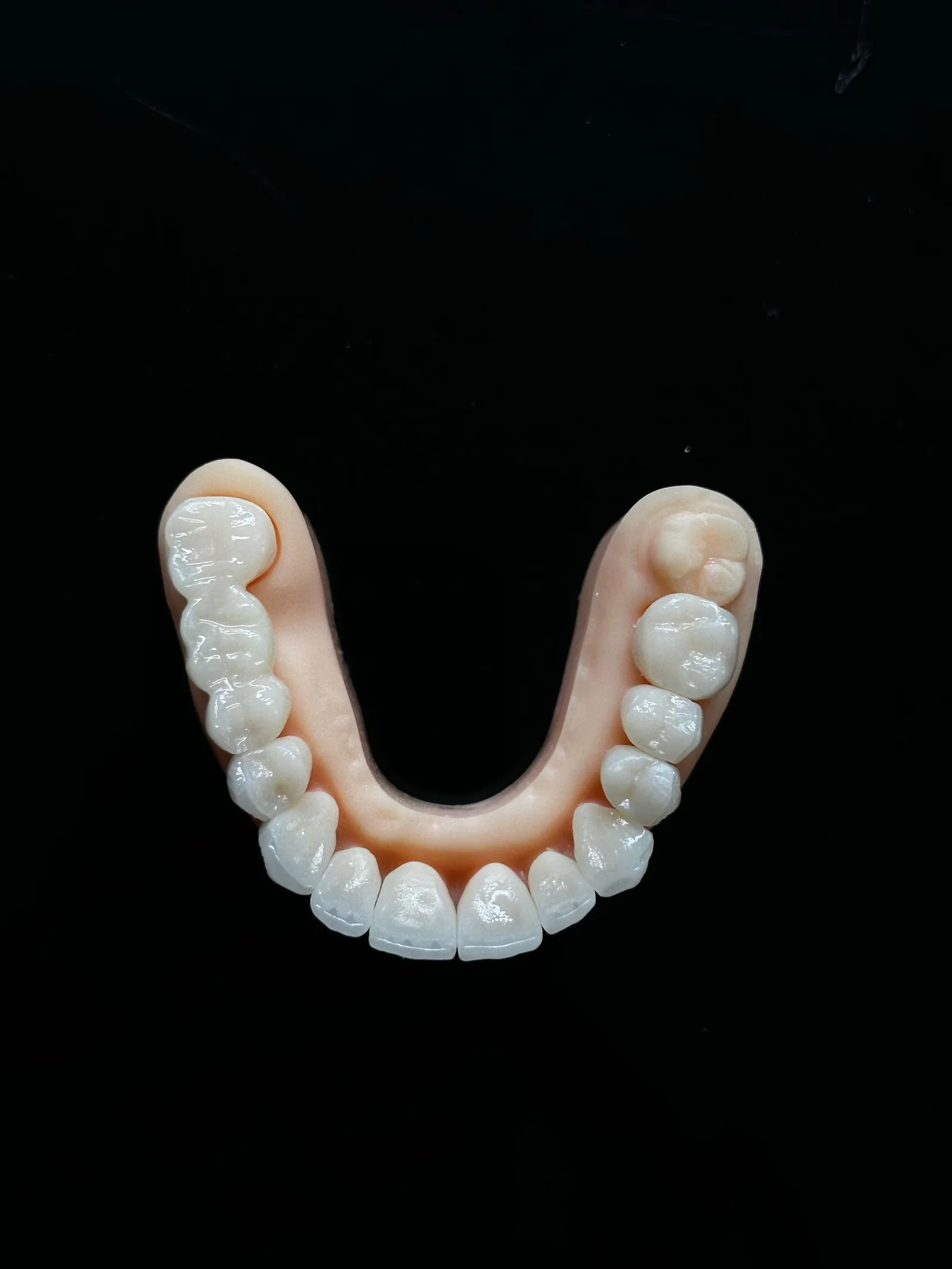 A lower denture on a dark surface.